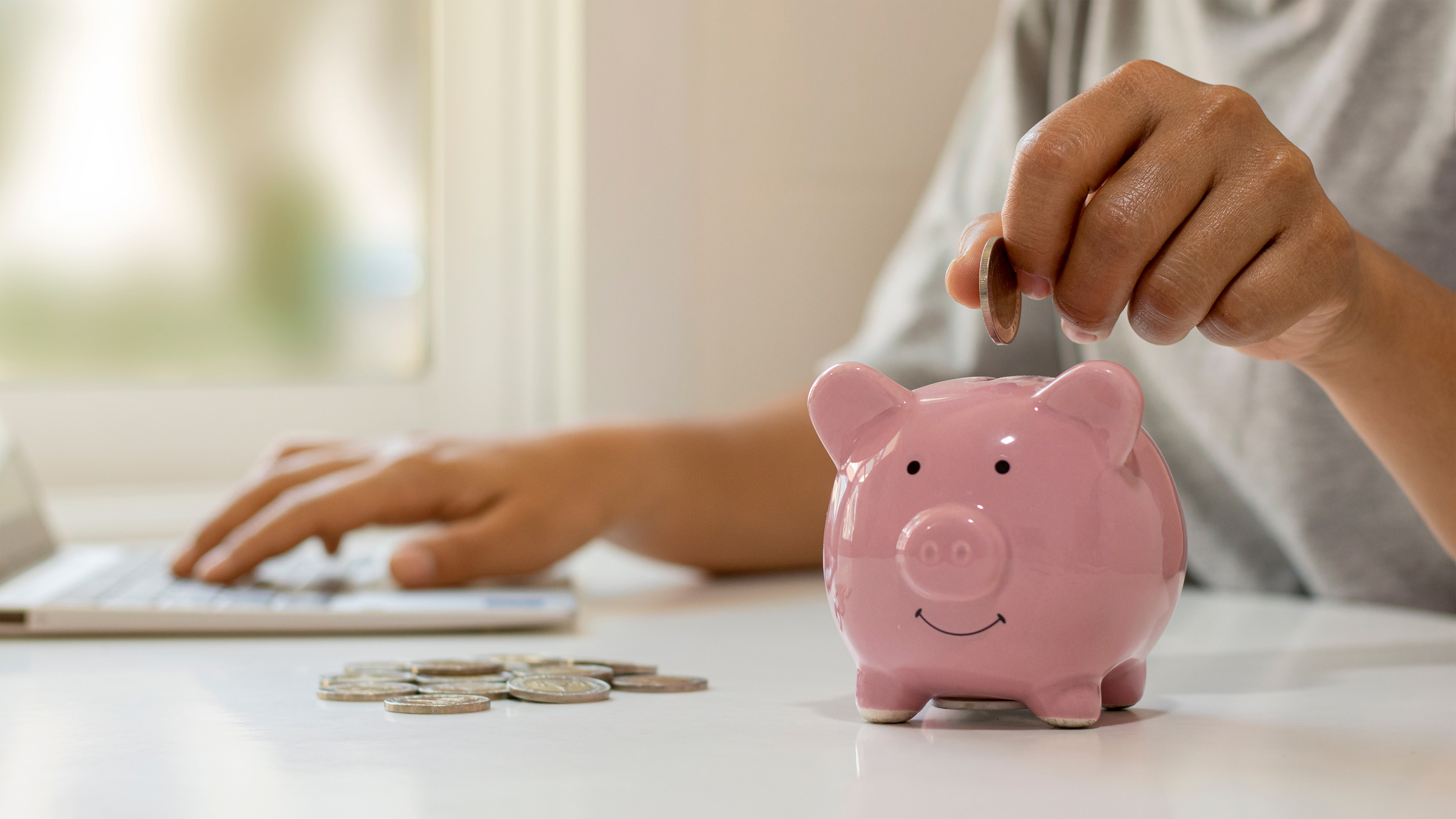 Person Dropping Coins into a Piggy Bank